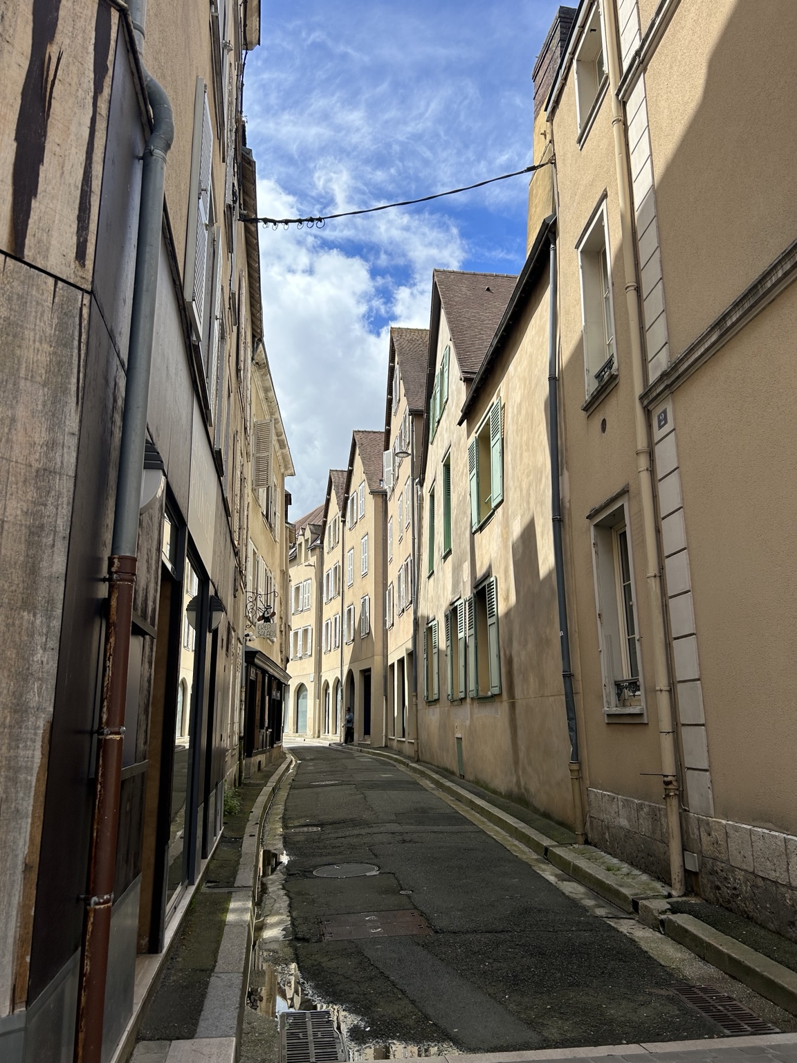 Sunlit narrow street lined with historic buildings